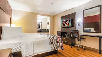 A hotel room with a bed, a desk, a television, a mirror, and a chair.
