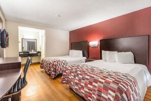 A hotel room with two beds, a desk, a chair, a mirror, and a red accent wall. - Red Roof Inn Phoenix - Midtown (Phoenix)