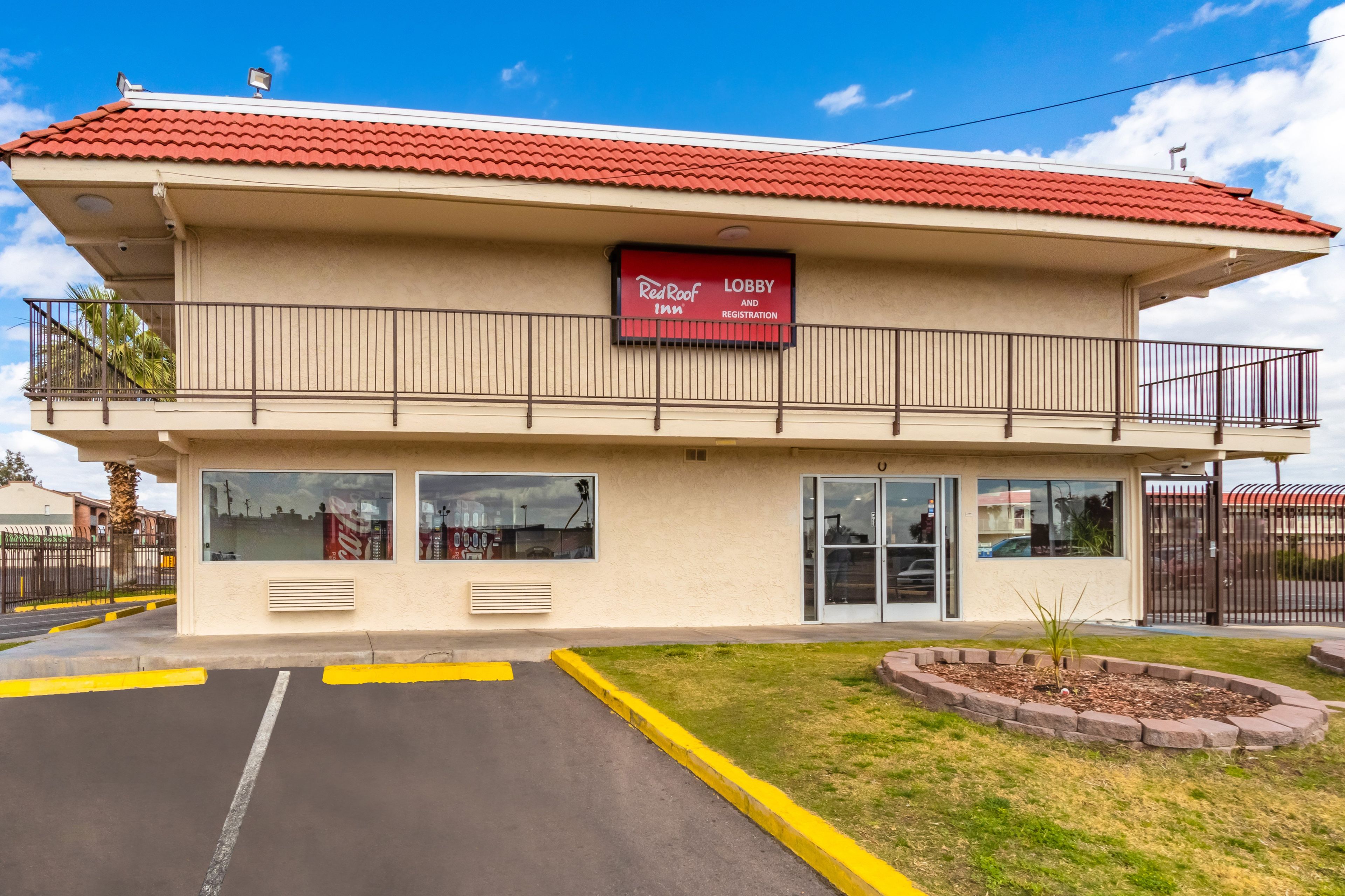 A two-story building with a red-tiled roof, a Coca-Cola sign, and a Red Roof Inn sign.