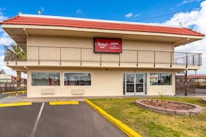 A two-story building with a red-tiled roof, a Coca-Cola sign, and a Red Roof Inn sign.