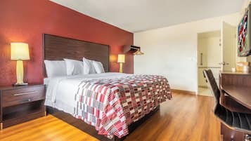 A hotel room with a bed, bedside tables, a desk, and a chair.