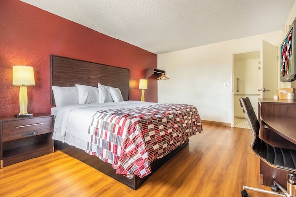 A hotel room with a bed, bedside tables, a desk, and a chair.