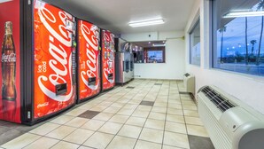 A row of Coca-Cola vending machines in a commercial space with tiled flooring and a window with a view of palm trees. - Red Roof Inn Phoenix - Midtown (Phoenix)