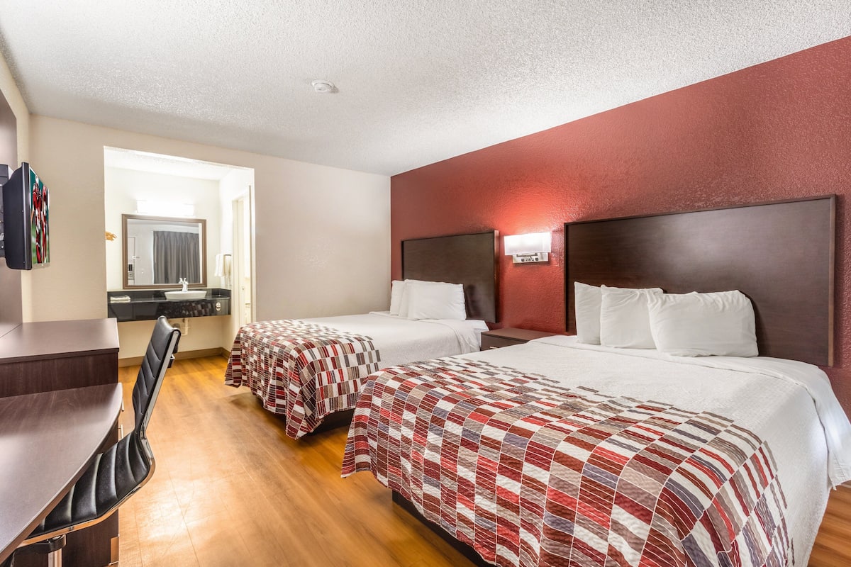 Ein Hotelzimmer mit zwei Betten, einem Schreibtisch und einem Stuhl.