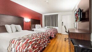 A hotel room with two beds, a TV, and a desk.