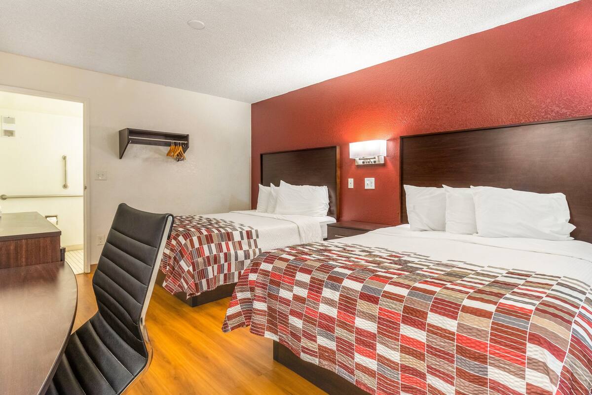 Ein Hotelzimmer mit zwei Betten, einem Schreibtisch und einem Stuhl.