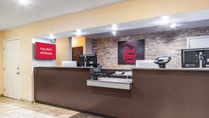 A hotel reception desk with a sign indicating free Wi-Fi in all rooms, a Red Roof Inn sign, and a security camera above the desk. - Red Roof Inn Phoenix - Midtown (Phoenix)