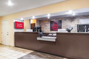 A hotel reception desk with a sign indicating free Wi-Fi in all rooms, a Red Roof Inn sign, and a security camera above the desk. - Red Roof Inn Phoenix - Midtown (Phoenix)