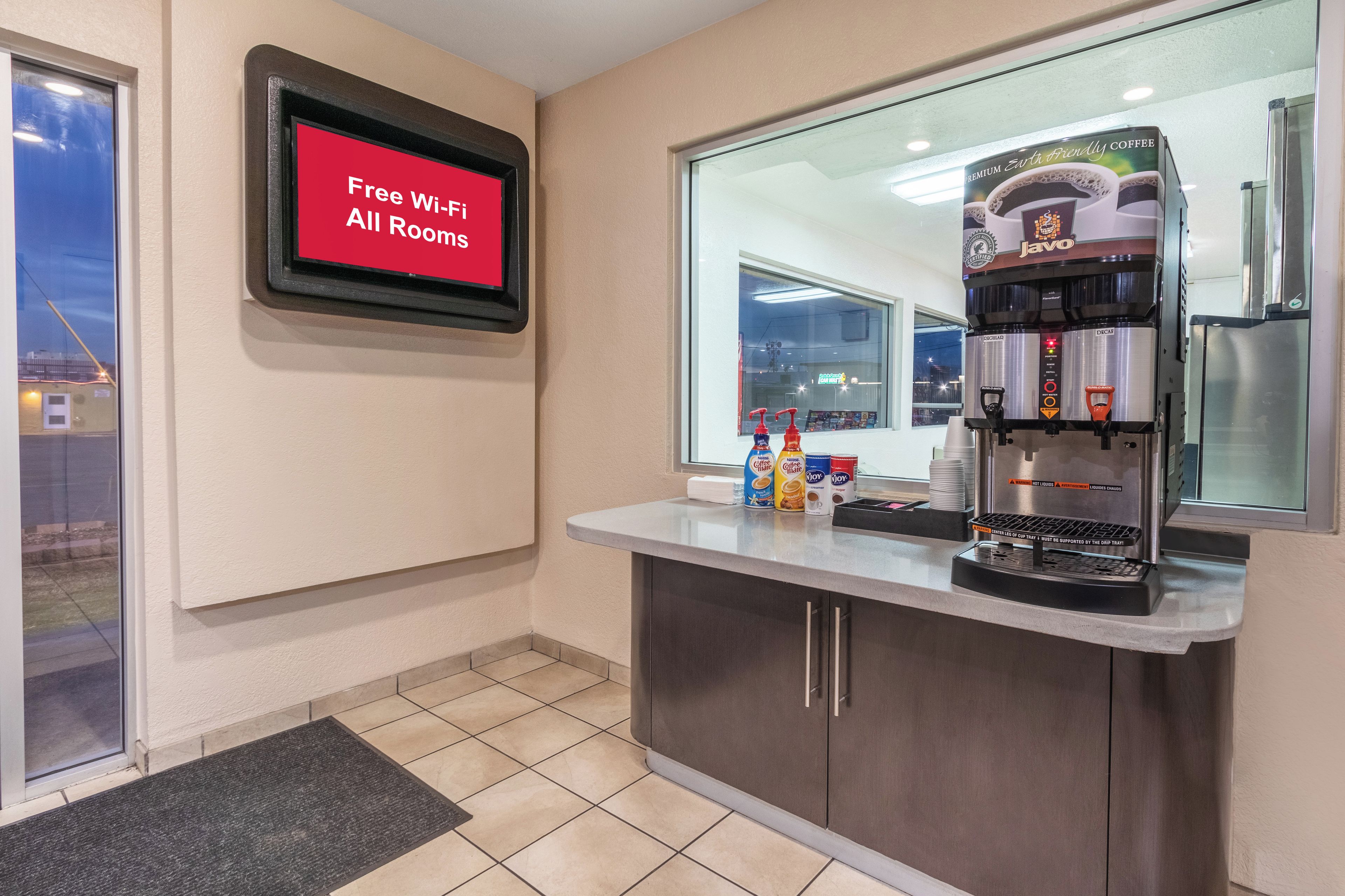 A coffee station with a Jovo branded coffee machine, free Wi-Fi sign, and a window view.