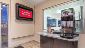 A coffee station with a Jovo branded coffee machine, free Wi-Fi sign, and a window view. - Red Roof Inn Phoenix - Midtown (Phoenix)