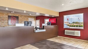 A hotel reception area with a reception desk, a digital screen advertising free Wi-Fi, and a view of the parking lot through a window.