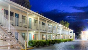 A motel with a two-story structure, a covered front porch, and a staircase leading to the entrance. - Motel 6 Bishop, CA (Bishop)