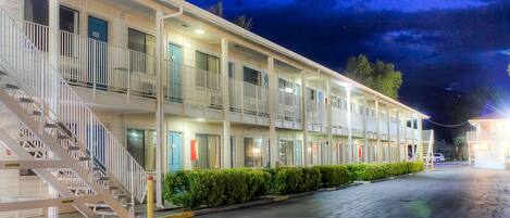 A motel with a two-story structure, a covered front porch, and a staircase leading to the entrance.