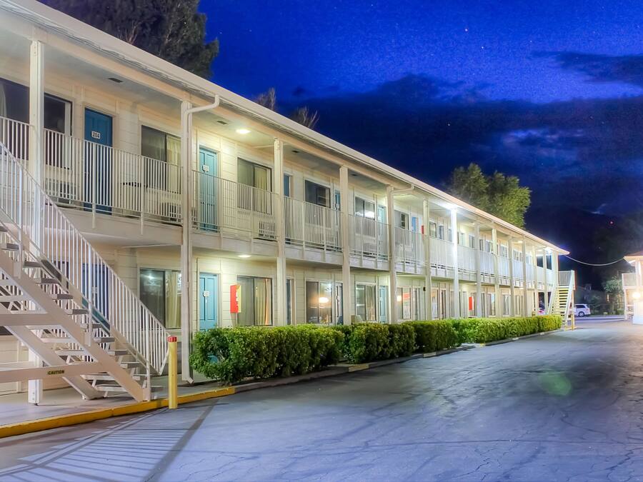 Um motel com estrutura de dois andares, varanda coberta na frente e escada que dá acesso à entrada.