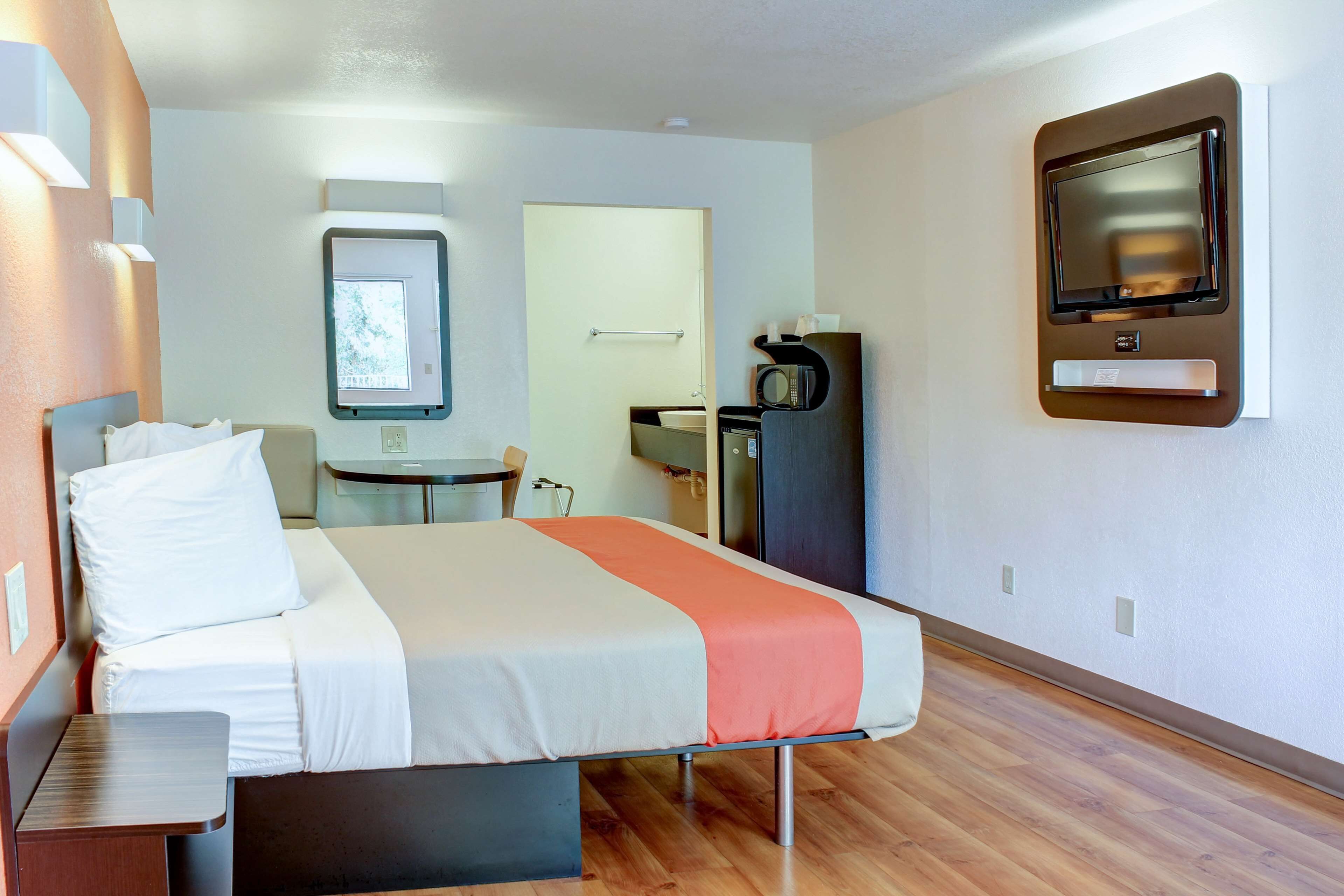 Camera d'albergo con un letto, una scrivania, un piccolo tavolo, un forno a microonde e una TV montata a parete.