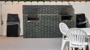 A patio area with a white fence, a brick wall, and a white chair. - Motel 6 Bishop, CA (Bishop)