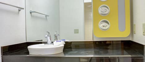 Un baño con un lavamanos blanco, un espejo y un toallero amarillo.