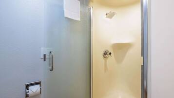 A bathroom with a glass shower enclosure, a towel dispenser, and a paper towel dispenser.