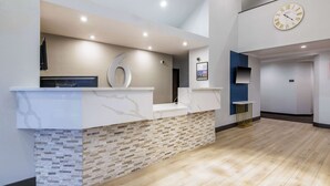 A reception area with a marble counter, a clock, and a modern design. - Motel 6 Auburn, CA (Auburn)
