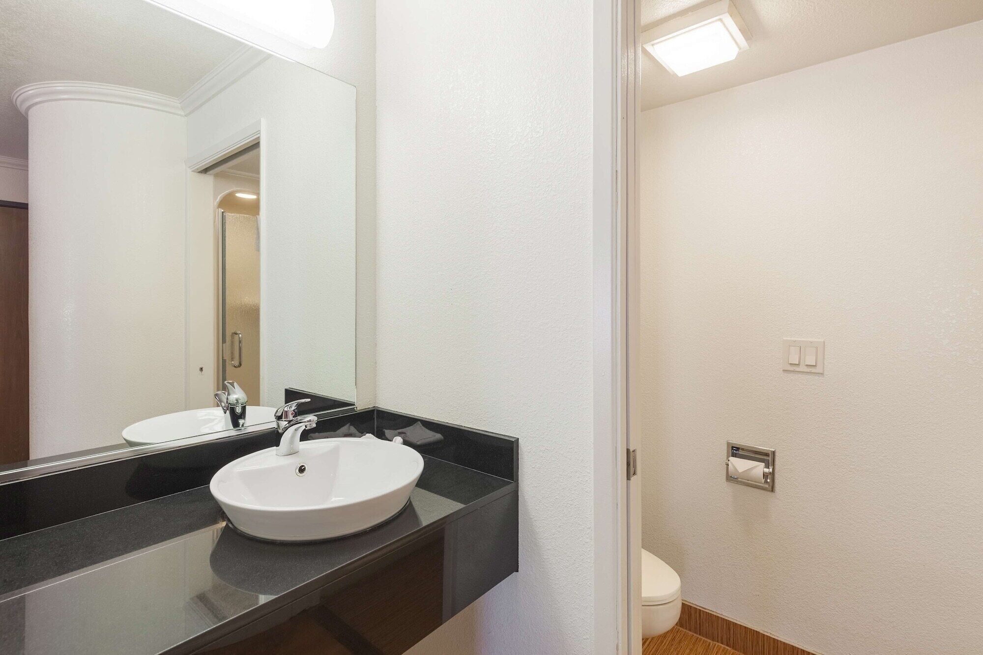 A bathroom with a white sink, a large mirror, and a toilet.