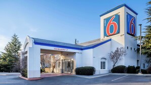 A motel with a prominent '6' sign, a clear entrance, and a 'Clearance 4' sign. - Motel 6 Auburn, CA (Auburn)