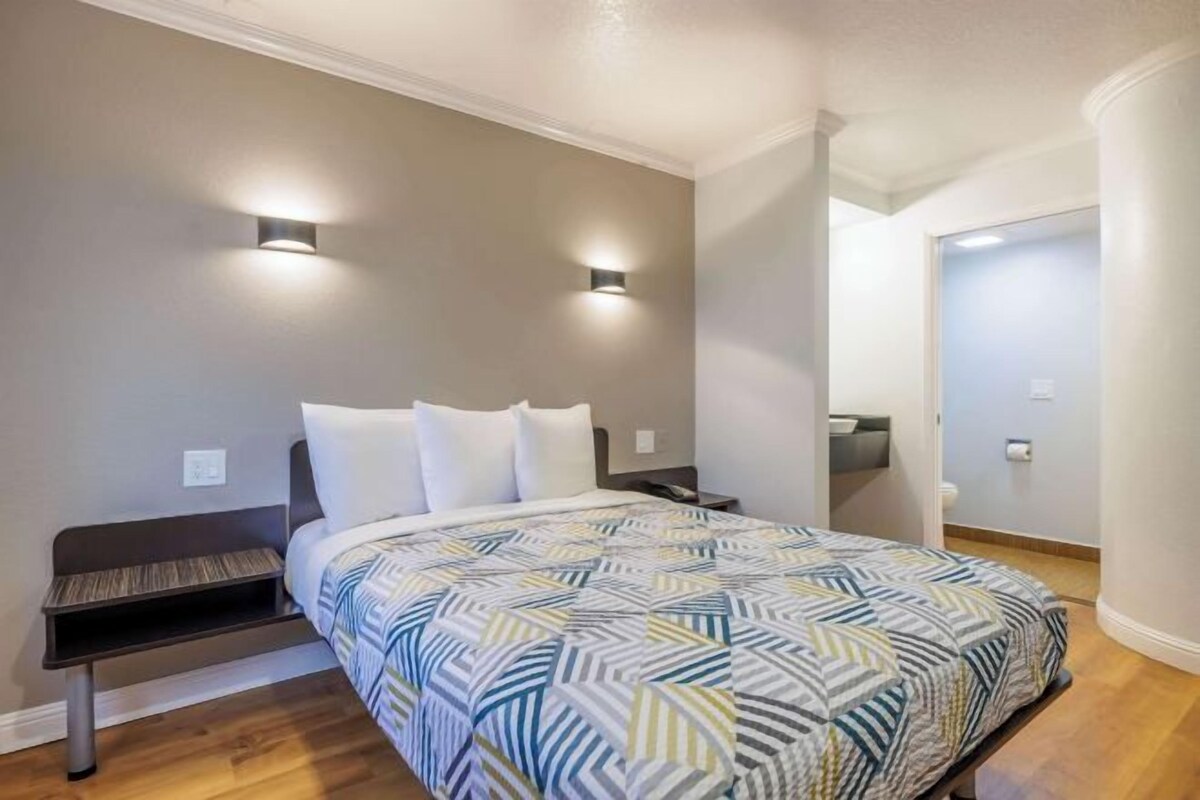 A bedroom with a bed, bedside tables, and two wall-mounted lights.