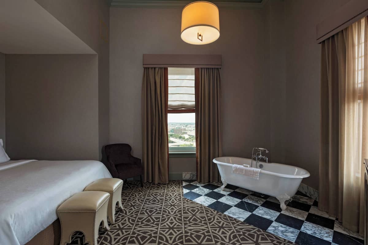 Una habitació d'hotel amb un llit gran, una banyera i un terra de pissos.