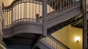 Una escalera de varios niveles con barandillas metálicas ornamentadas y escalones de madera.