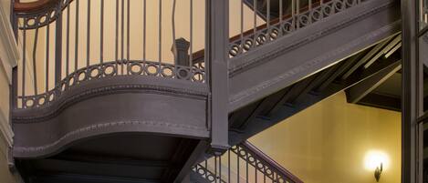 Una escalera de varios niveles con barandillas metálicas ornamentadas y escalones de madera.