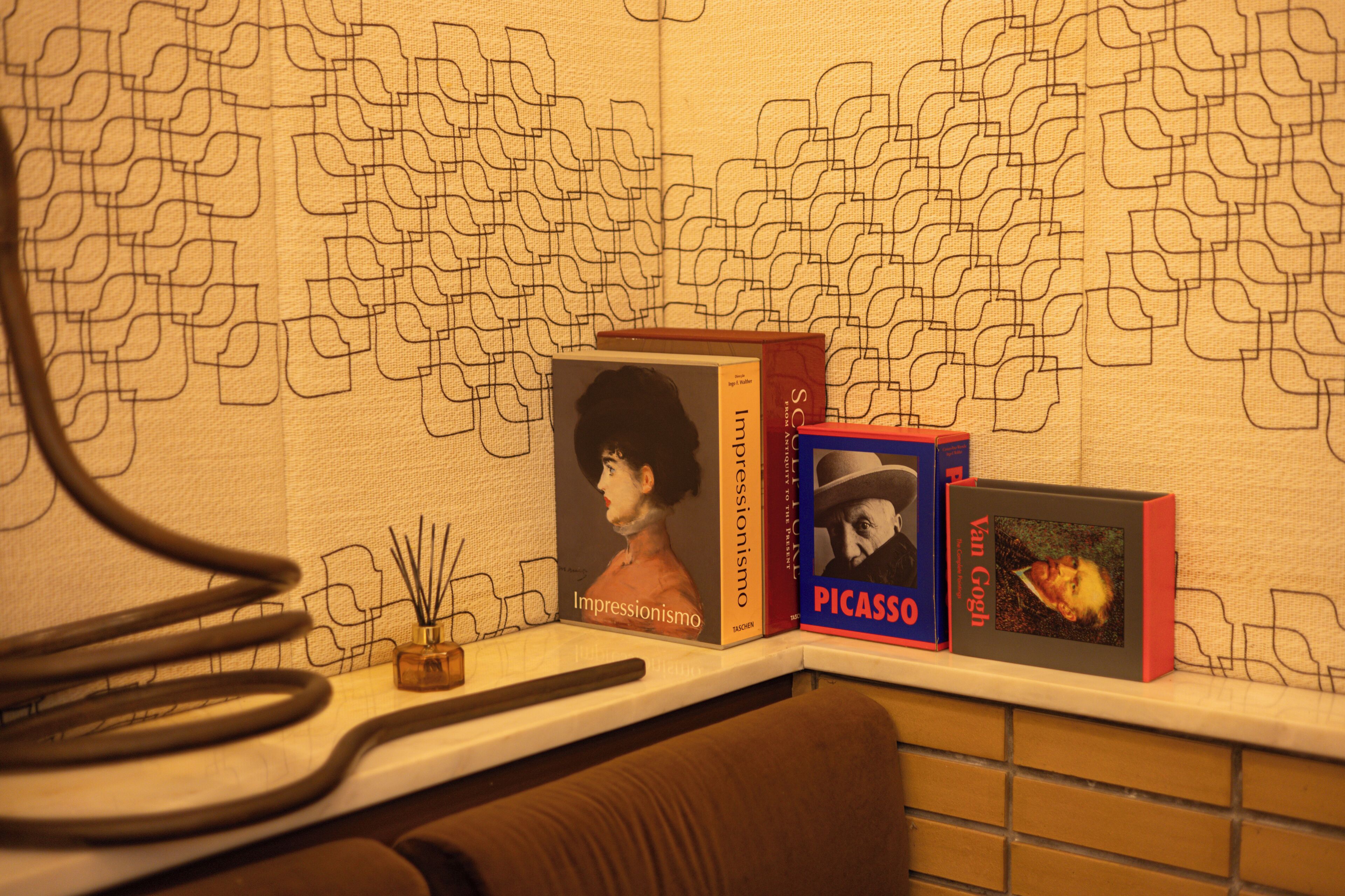 Una estantería con libros, incluyendo títulos como "Impressionism" y "Picasso".