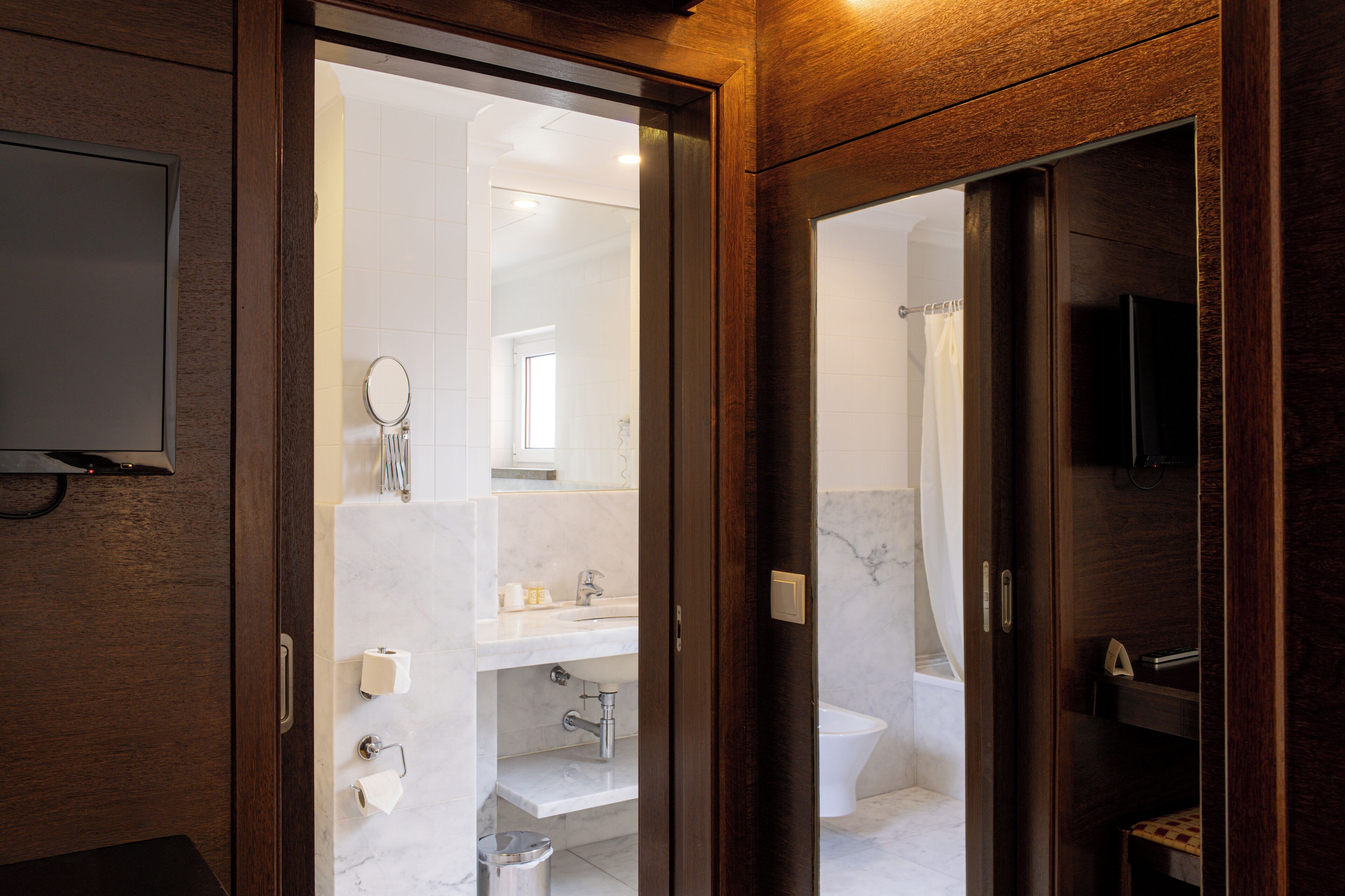 A modern bathroom with a large mirror, a toilet, and a sink.