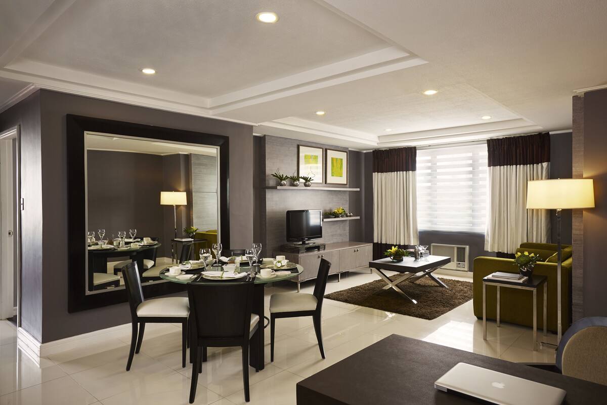 A modern living room with a dining area, a flat-screen TV, and a sofa.