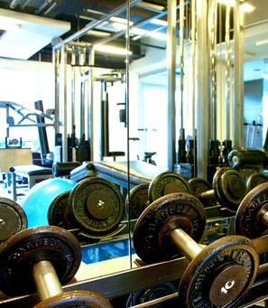 A gym with various exercise equipment, including dumbbells and weight plates. - Astoria Plaza (Pasig)