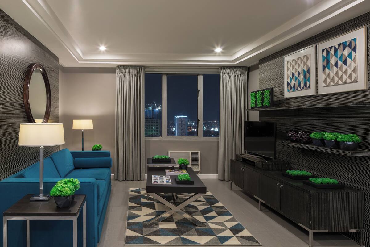 A modern living room with a sofa, coffee table, and a view of the city at night.