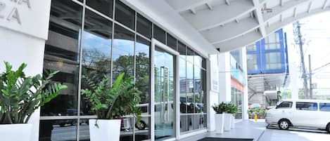 Un edificio moderno con amplios ventanales de vidrio, paredes exteriores blancas y plantas en macetas.