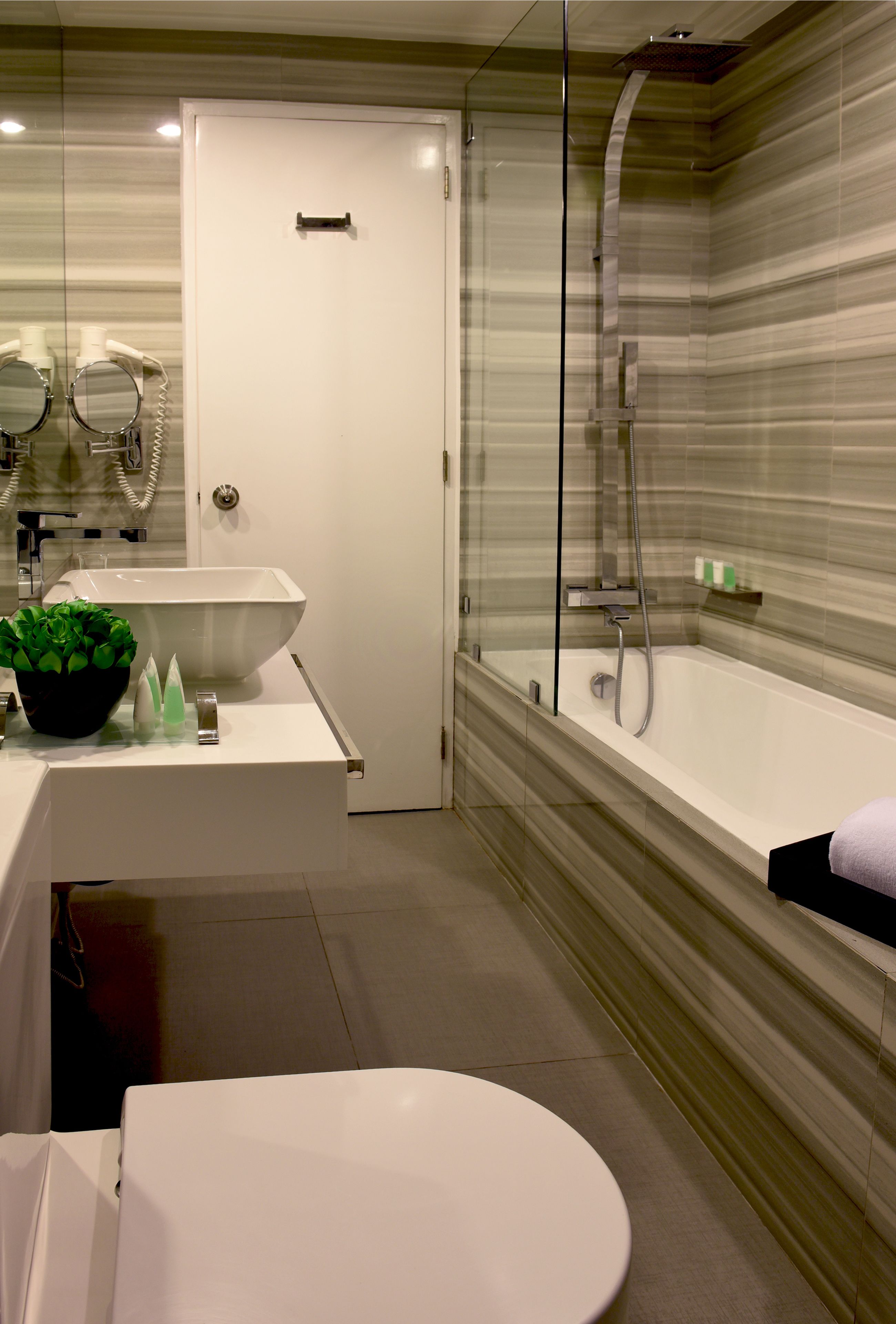 Een moderne badkamer met een douchecabine van glas, een wit wastafelmeubel en een toilet.