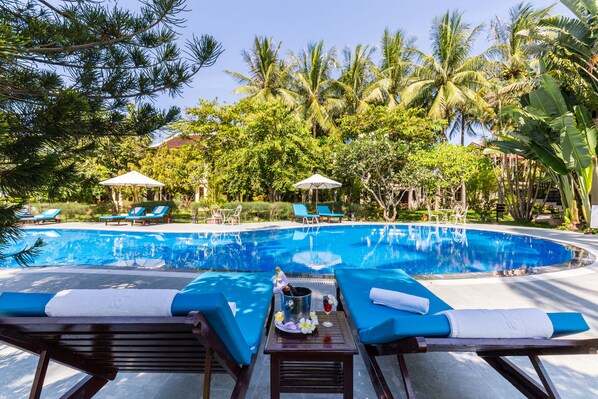 Una piscina al aire libre, sombrillas, tumbonas