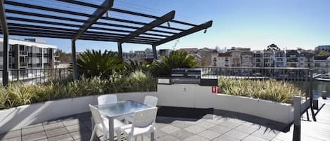 En tagterrasse med pergola, siddeområde og udsigt over bybilledet.
