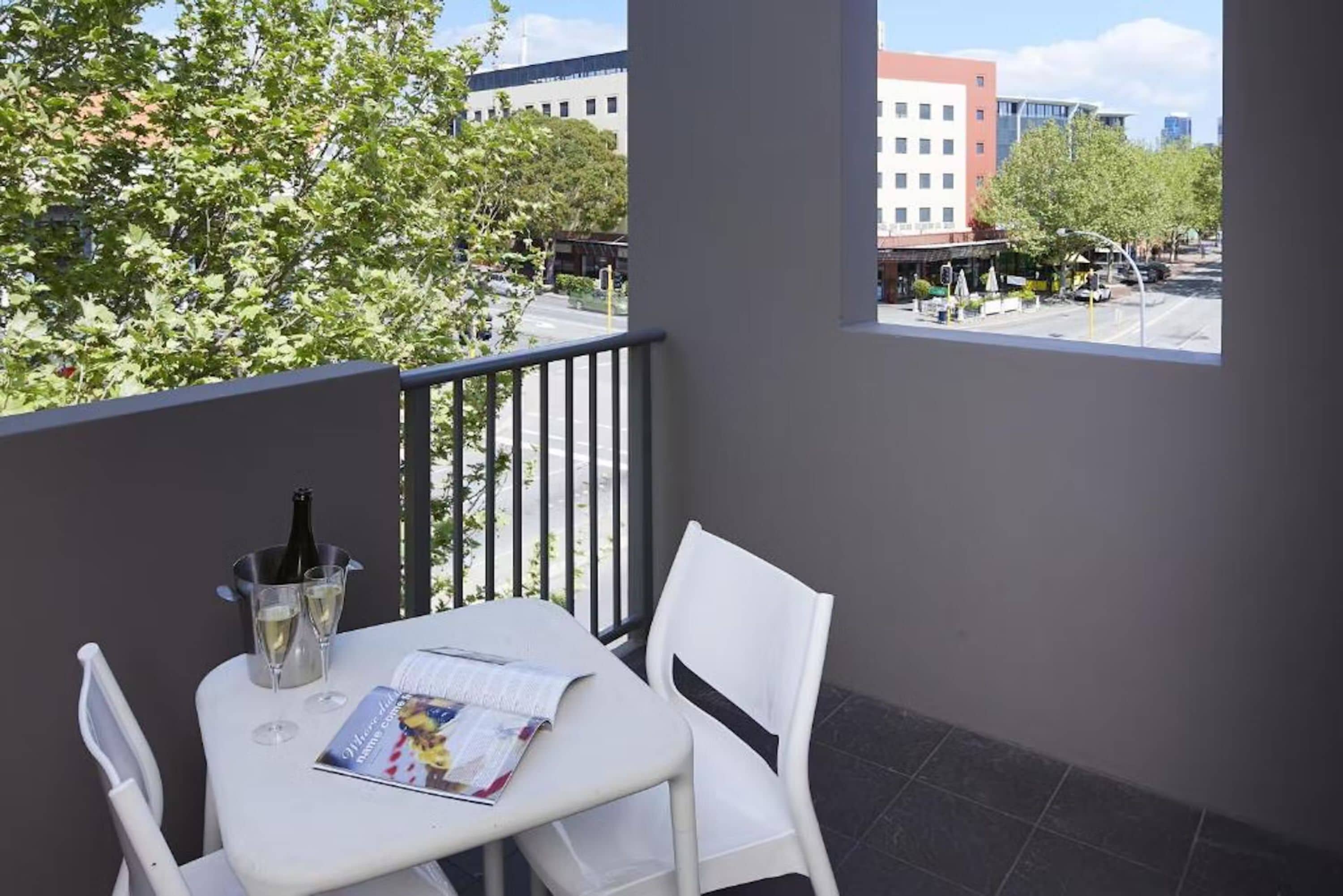 Un balcón con una mesa lista para dos personas, una botella de champán y una revista.