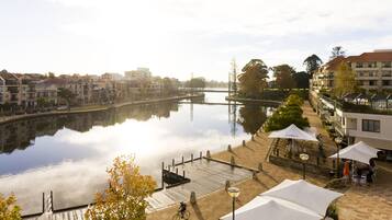 Vista del río con un muelle, asientos al aire libre y edificios a lo largo de la orilla.