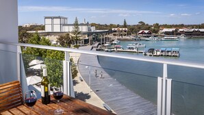 A balcony with a wooden table, two wine glasses, and a bottle of wine. - East Perth Suites Hotel (East Perth)