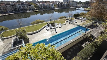 Una piscina al aire libre, sombrillas, tumbonas