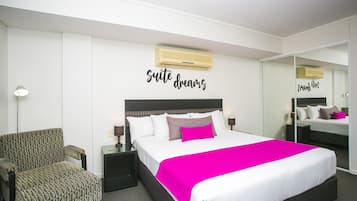 Una habitación de hotel con cama, una silla, una mesita de noche y un espejo.