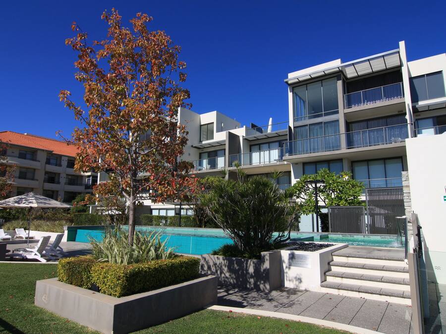 Un edificio moderno con piscina, asientos al aire libre y una escalera que lleva a un balcón.