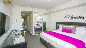 A hotel room with a bed, a desk, a mirror, and a wall with the text "suite dreams". - East Perth Suites Hotel (East Perth)