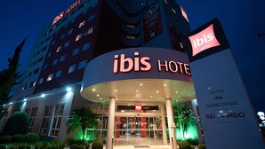A hotel with a prominent 'ibis HOTEL' sign, a modern architectural design, and a well-lit entrance.