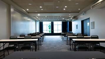 A conference room with multiple tables and chairs, a projector, and large windows.