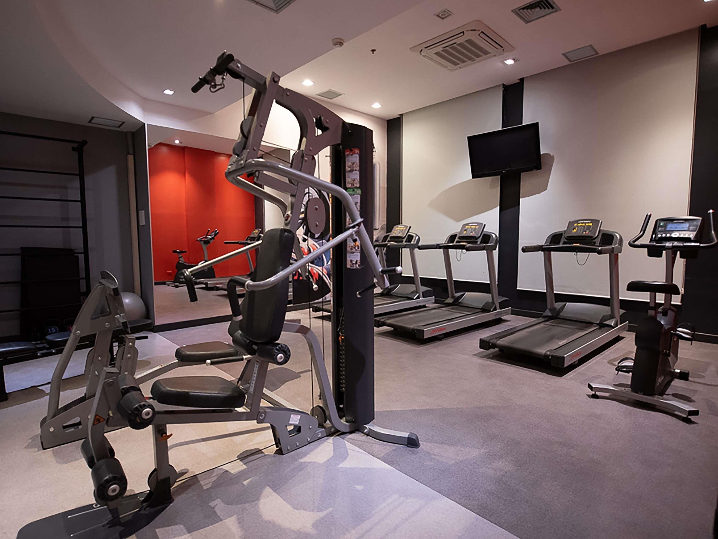 Uma academia com diversos equipamentos de exercício, incluindo esteiras e aparelhos de musculação.