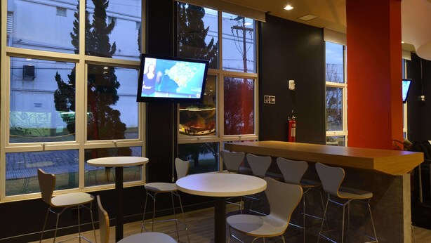 A modern bar area with a television, multiple seating options, and large windows offering views of the outside.