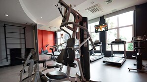 A gym with exercise equipment, a treadmill, and a TV screen.